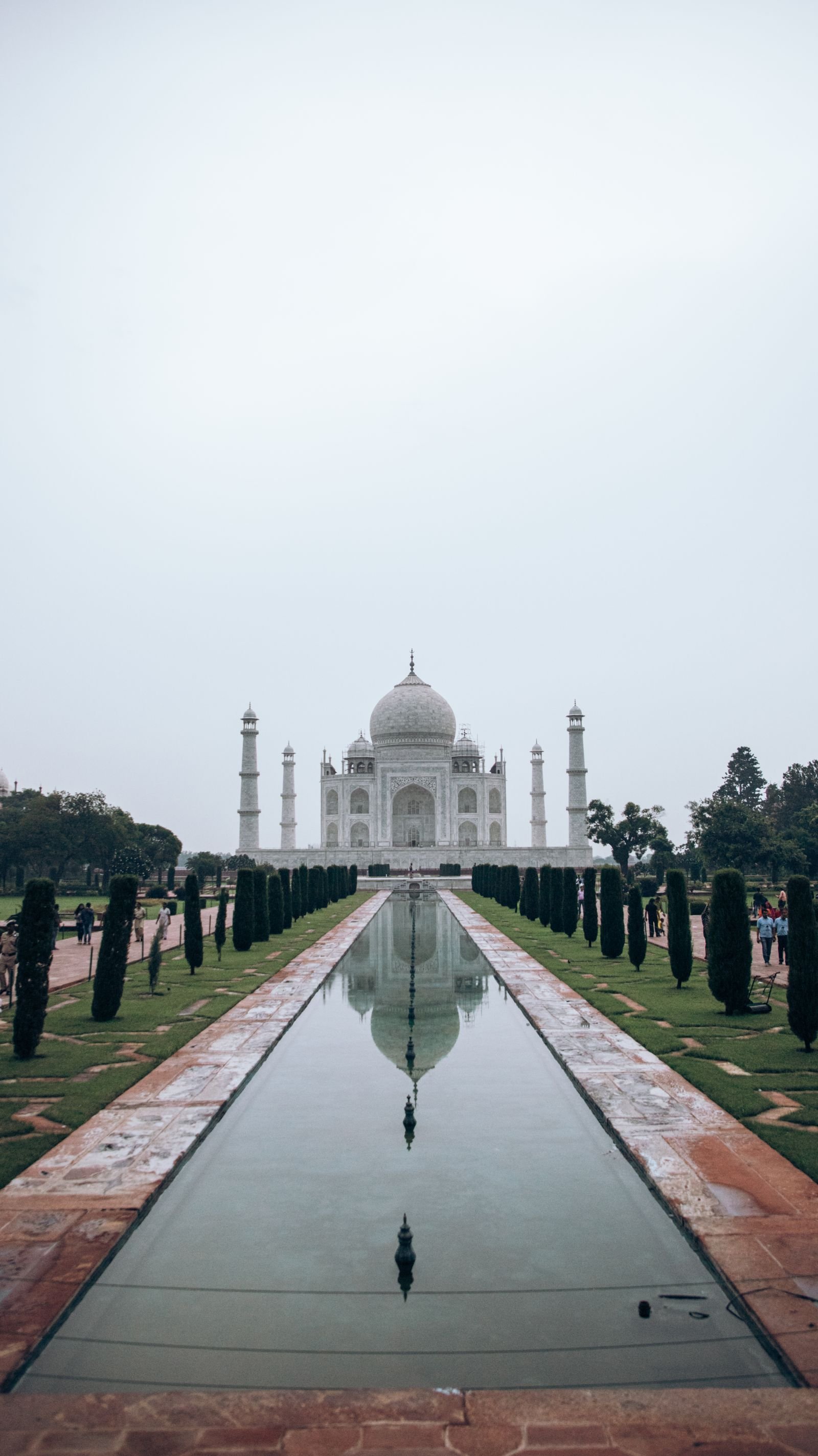 Taj Mahal fotografado em composição centralizada e simétrica, refletido no espelho d'água à sua frente