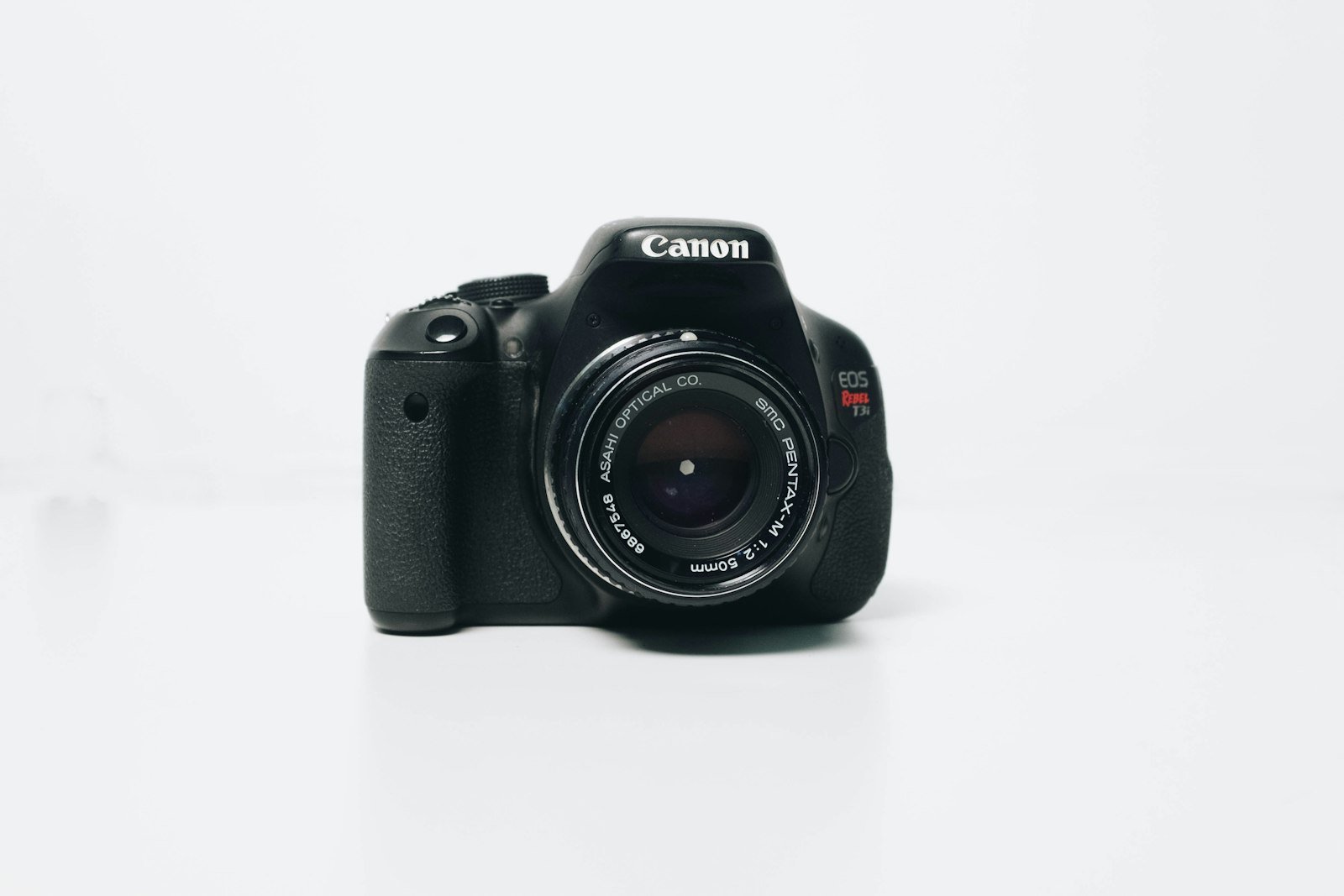 Câmera DSLR Canon EOS Rebel vista de frente sobre fundo branco, mostrando o corpo compacto com o visor óptico saliente no topo